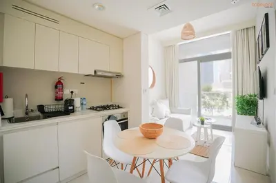 a kitchen with a table and white chairs in a kitchen at Bnbeyond's Serene Poolside Bliss in Dubai