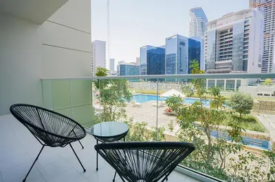 a balcony with two chairs and a glass table at Bnbeyond's Serene Poolside Bliss in Dubai