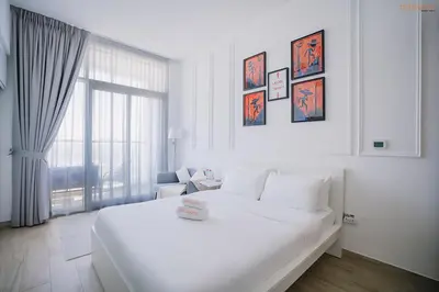a white bedroom with a large white bed and a window at Bnbeyond's Modern Marina Pad in Dubai