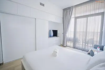 a white bedroom with a large window and a tv at Bnbeyond's Modern Marina Pad in Dubai