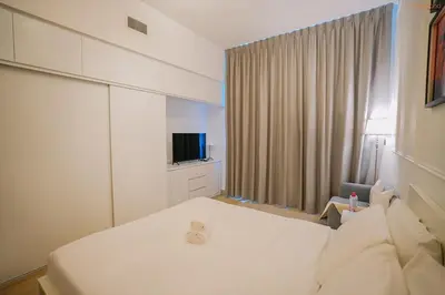 a bedroom with a white bed and a television at Bnbeyond's Modern Marina Pad in Dubai