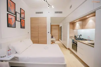 a bedroom with a white bed and a kitchen at Bnbeyond's Modern Marina Pad in Dubai