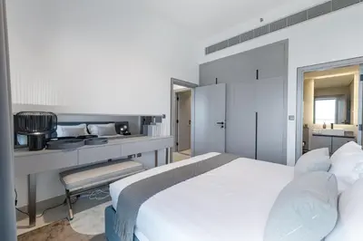 a bedroom with a white bed and a kitchen at ALiving Modern & Chic 1BR I MAG960 in Dubai