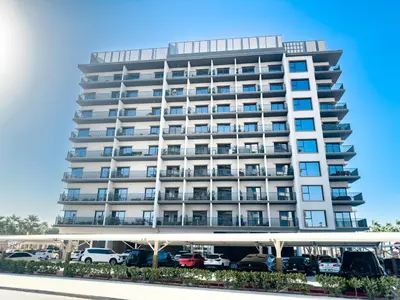 a tall white building with cars parked in a parking lot at ALiving Modern & Chic 1BR I MAG960 in Dubai