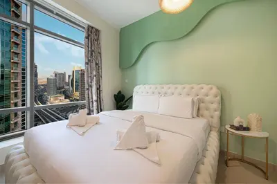 a bedroom with a white bed with a large window at Serene Cozy 2BR Near Burj Khalifa in Dubai