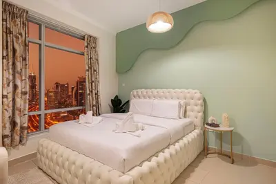 a bedroom with a white bed with a large window at Serene Cozy 2BR Near Burj Khalifa in Dubai