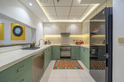 a kitchen with green cabinets and a tile floor at Cityscape & Coastal Charm Elegant 2BR Seaside in Dubai Marina