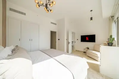 a white bedroom with a large bed and a tv at High-Floor 1BR New Design Steps to JBR Beach in Dubai