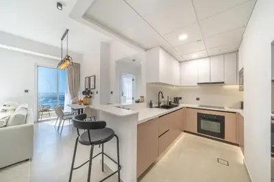 a kitchen with a counter and chairs in a room at High-Floor 1BR New Design Steps to JBR Beach in Dubai