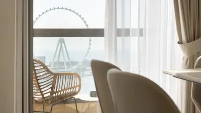 a room with chairs and a window with a ferris wheel at High-Floor 1BR New Design Steps to JBR Beach in Dubai