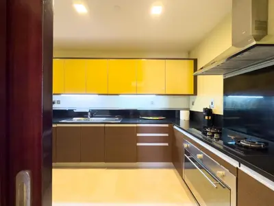 a kitchen with wooden cabinets and yellow cabinets at Luxury 2BR plus Maidrm at Grandeur Res Palm Jumeir in Dubai