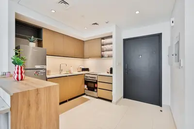 a kitchen with wooden cabinets and a black door at Venetian - Wake up to Burj Khalifa views in Downtown Dubai in Dubai