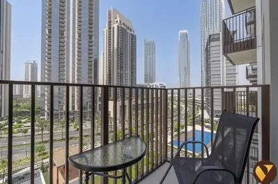 a balcony with a table and chairs and a view of a city at Vogue Creek Harbour Creek Crescent Waterfront Living Close to Downtown, Burj Khalifa and Dubai Mall, One Bedroom Apartment with Balcony and City View, Access to all Amenities in Dubai