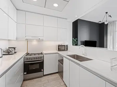 a white kitchen with a stove and a sink at Chic City Escape - 2BR Plus Guest Room at Atria, Business Bay in Dubai