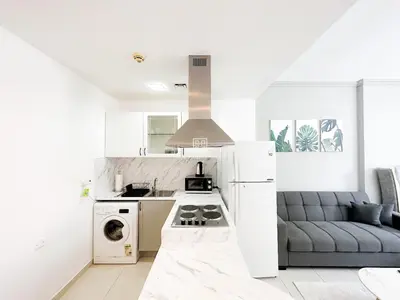 a white kitchen with a couch and a stove at Fully Furnished Studio at Spring Oasis in Dubai Silicon Oasis in Dubai
