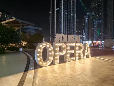 a large sign that says open on a city street at night at FAM Living Act Two 1BR Walk to Burj & Dubai Mall in Dubai