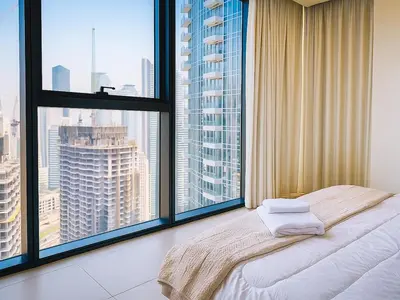 a bedroom with large windows and a bed with white sheets at Dream Shoma Upscale 3BR in Downtown Dubai in Dubai