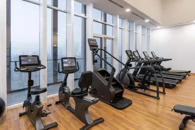 a gym with treadmills and ellipticals in a room with windows at BLVD - Upgraded Highrise Suites in Dubai