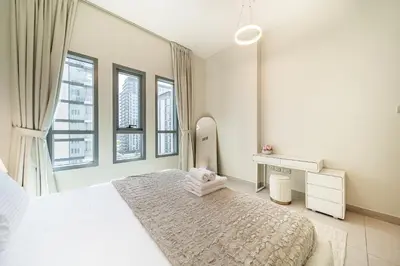 a white bedroom with a large bed and a mirror at Luxury unit in the Heart of Dubai Hills in Dubai