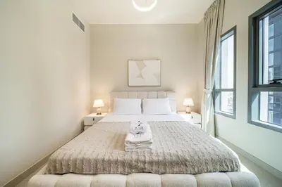 a white bedroom with a large bed with two lamps at Luxury unit in the Heart of Dubai Hills in Dubai