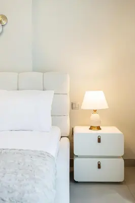 a white bed with a lamp on a night stand next to a bed at Luxury unit in the Heart of Dubai Hills in Dubai