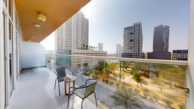 a balcony with two chairs and a view of a city at Vacationer I JVC Gem 1 Bedroom I Free Pool, Gym, Parking & Wi-Fi in Dubai