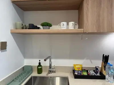 a kitchen counter with a sink and some cups on a shelf at Cozy Studio with Balcony Pool View - Business Bay in Dubai