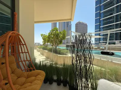 a living room with a chair and a large window at Cozy Studio with Balcony Pool View - Business Bay in Dubai
