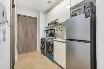a kitchen with a refrigerator and a stove at DAYF-SER08 Brand New Studio with Balcony in JVC in Dubai
