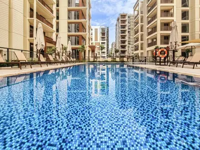 a large blue swimming pool with chairs and buildings at 1BD Apartment at Creek Beach with Lagoon Access in Dubai
