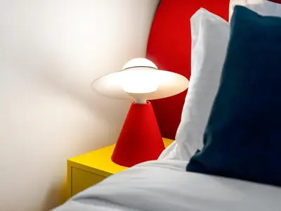 a red lamp on a side table next to a bed at Amazing Design Colorfull Flat Palm Jumeirah View in Heart of Marina in Dubai