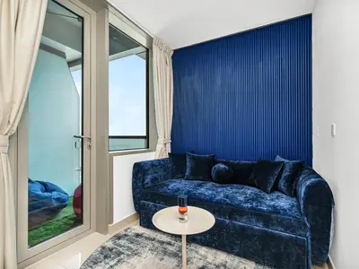a living room with a blue couch and a table at Amazing Design Colorfull Flat Palm Jumeirah View in Heart of Marina in Dubai