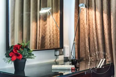 a desk with a vase with a red flower on it at Luxurious Studio Flat with Burj Khalifa Views in Dubai