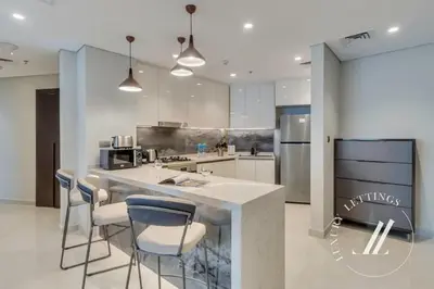 a kitchen with a counter and some chairs in it at Luxury 2BDR Apartment with Private Balcony in Dubai