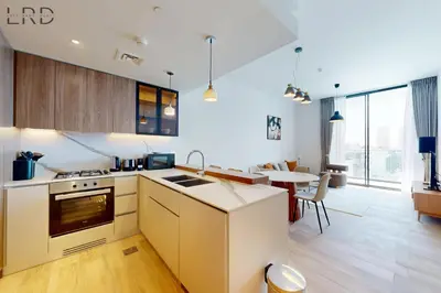 a kitchen with white cabinets and a table in a room at Brand New and Modern 1BR in Dubai
