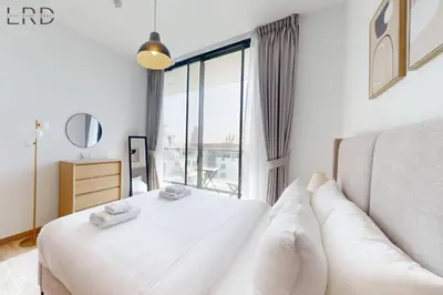 a bedroom with a white bed and a large window at Brand New and Modern 1BR in Dubai