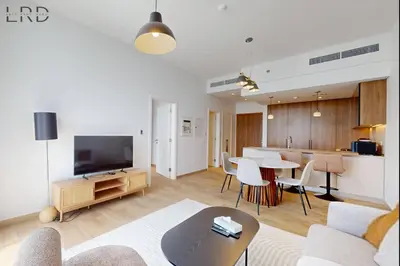 a living room with a table and a kitchen at Brand New and Modern 1BR in Dubai