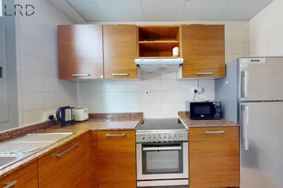 a small kitchen with wooden cabinets and a refrigerator at Cozy Studio in Dubai Marina in Dubai