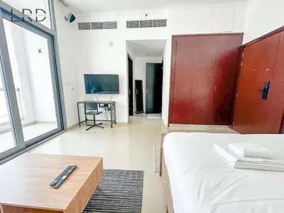 a bedroom with a bed and a table and a tv at Cozy Studio in Dubai Marina in Dubai