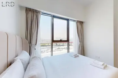 a bedroom with a white bed and a large window at Modern 1BR with Canal View in Dubai