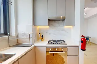 a kitchen with white cabinets and a stove top oven at Modern 1BR with Canal View in Dubai
