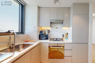 a white kitchen with a sink and a stove at Cozy 1BR with Canal View in Dubai