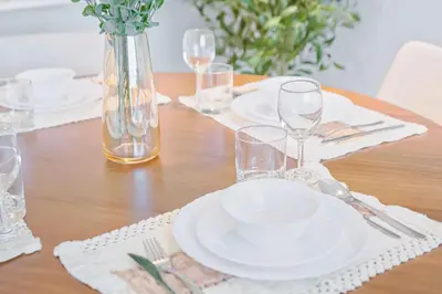 a wooden table with white plates and glasses on it at PVH - Vibrant 1BR - Binghatti Corner in Dubai