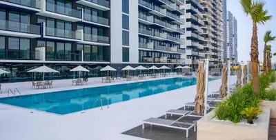 a swimming pool with chairs and umbrellas in front of a building at PVH - Vibrant 1BR - Binghatti Corner in Dubai