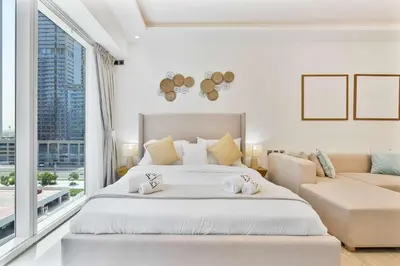 a white bedroom with a large bed and a couch at PVH - Chic Furnished Studio in JLT - Me Do Re in Dubai