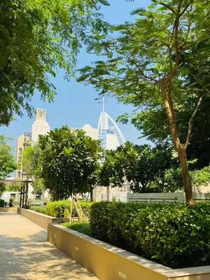 a park with the london eye in the background at Rahaal 1 BDR, Madinat Jumeirah in Dubai