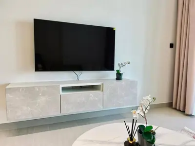 a living room with a television on a silver entertainment center at Velvet 1br Serenity Pool View & Free Amenities! in Dubai