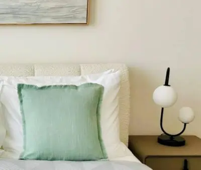 a bed with a green pillow and a lamp on a table at Sky 2br Sanctuary With Plunge Pool Gym Parking! in Dubai