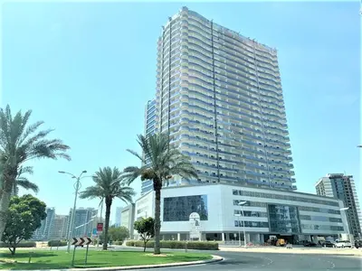 a large building with palm trees in front of it at Luxury Studio Pool & Gym Access in Dubai Sports City in Dubai