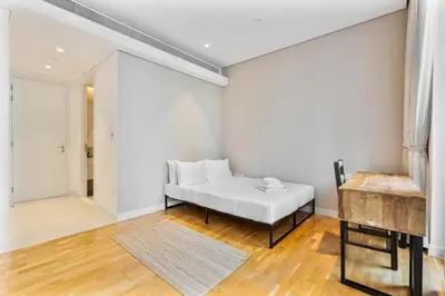 a white room with a bed and a wooden floor at PVH - Tranquil 2BR - Bluewaters Residences 5 in Dubai